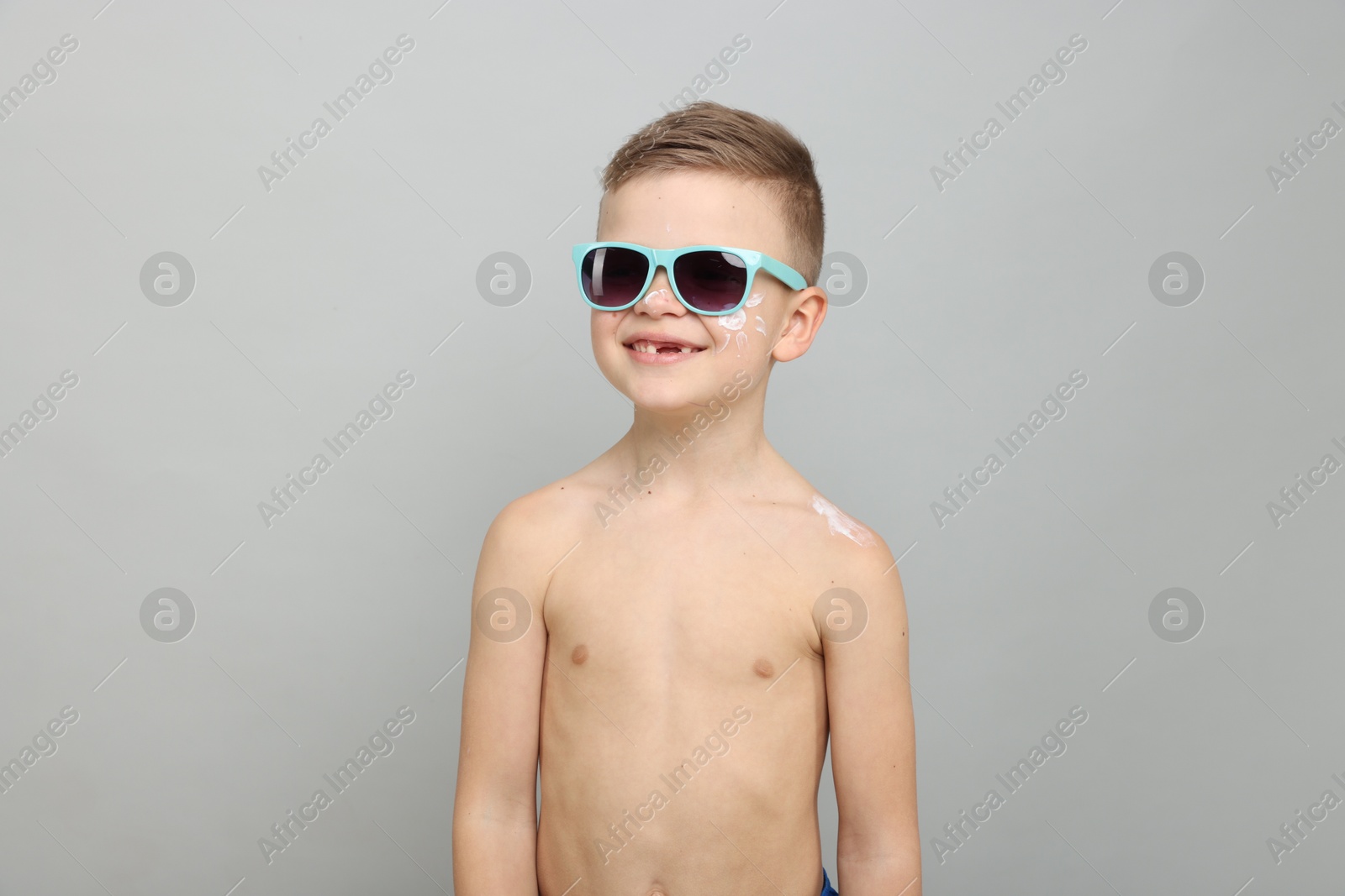 Little boy with sun protection cream on his skin against light grey background Photo of Little boy with sun protection cream on his skin against light grey background