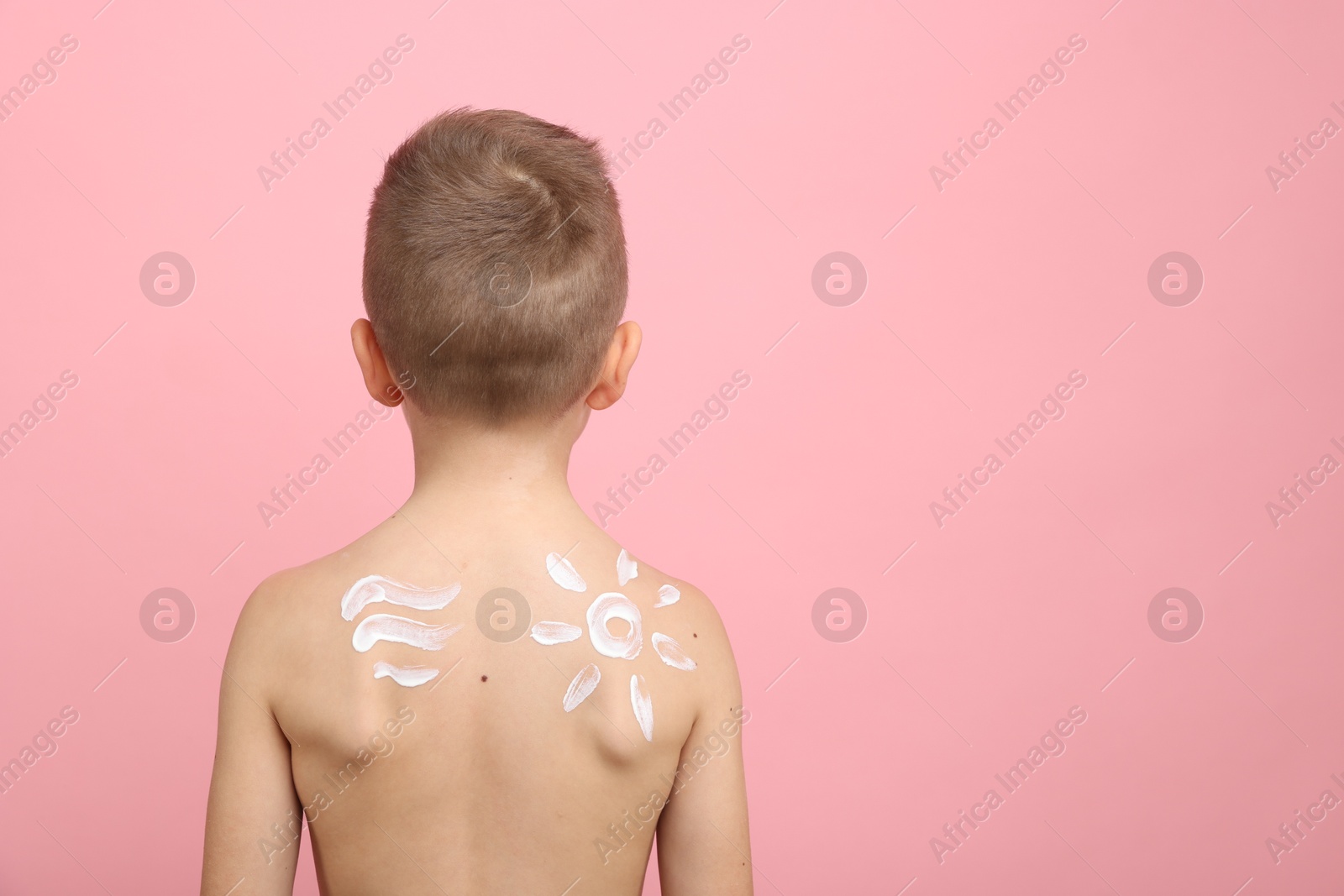 Little boy with sun protection cream on his skin against pink background, back view. Space for text Photo of Little boy with sun protection cream on his skin against pink background, back view. Space for text