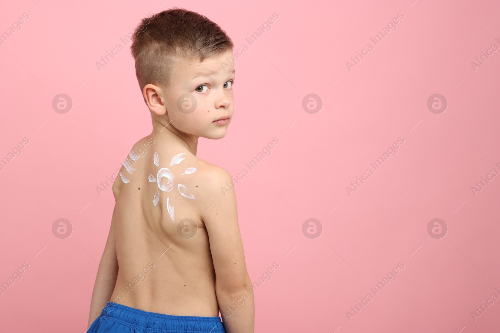 Little boy with sun protection cream on his skin against pink background, space for text Photo of Little boy with sun protection cream on his skin against pink background, space for text