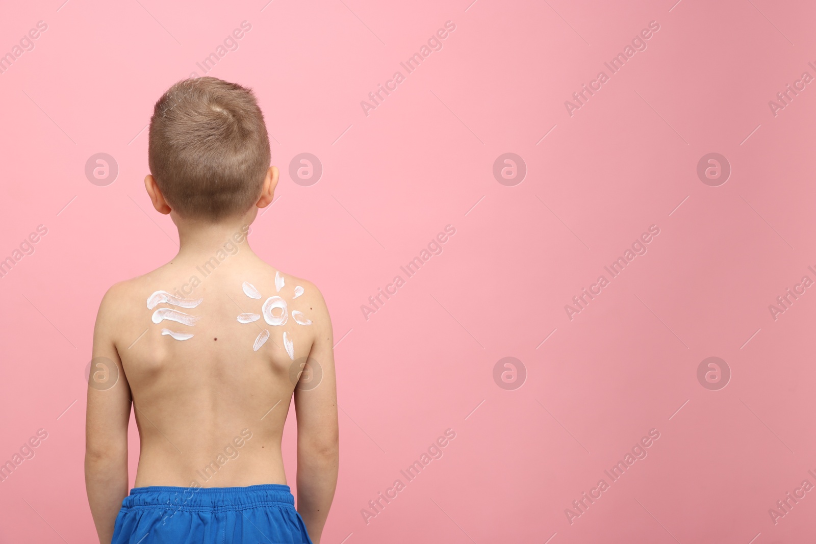 Little boy with sun protection cream on his skin against pink background, back view. Space for text Photo of Little boy with sun protection cream on his skin against pink background, back view. Space for text