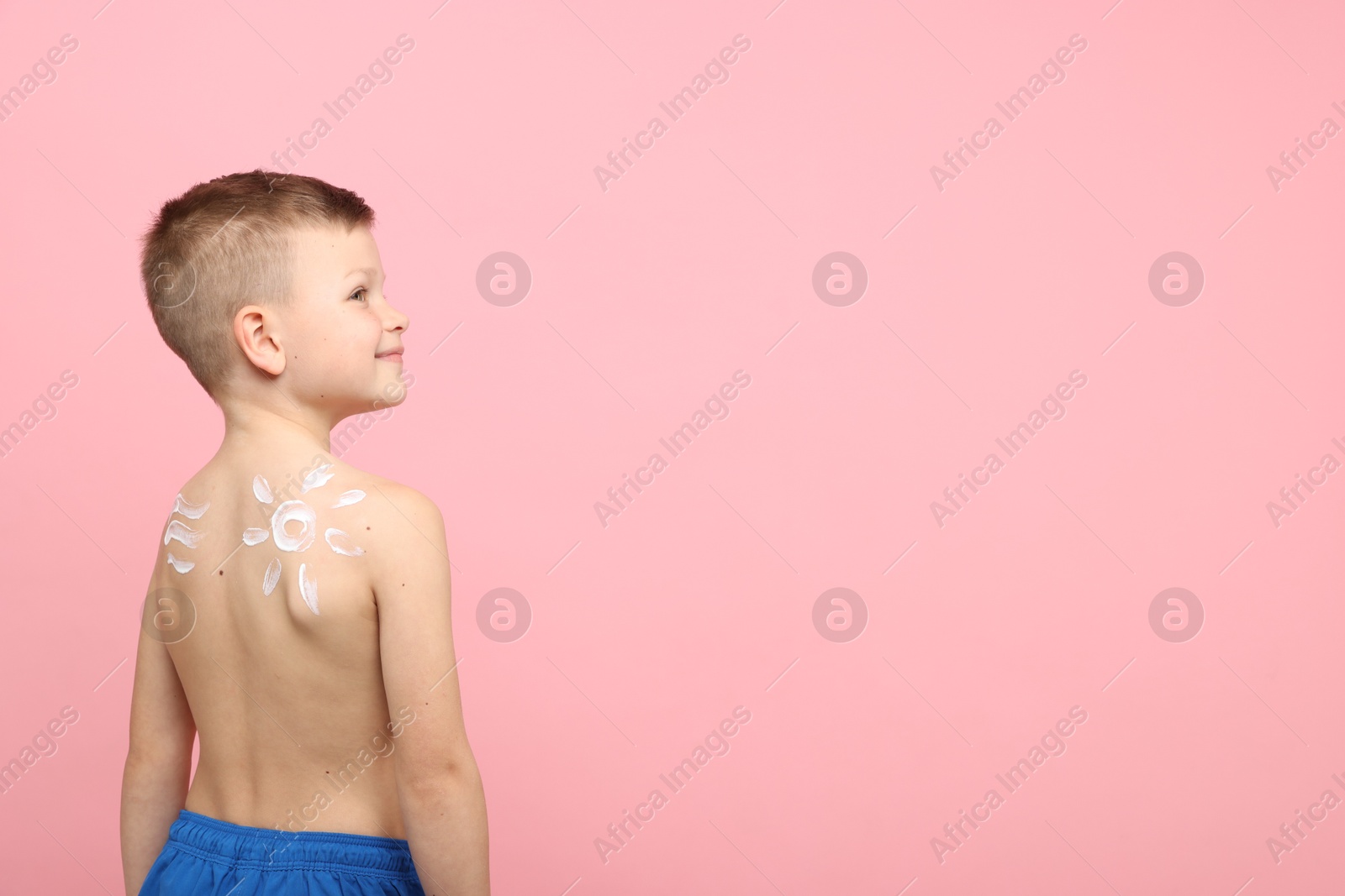 Little boy with sun protection cream on his skin against pink background, back view. Space for text Photo of Little boy with sun protection cream on his skin against pink background, back view. Space for text