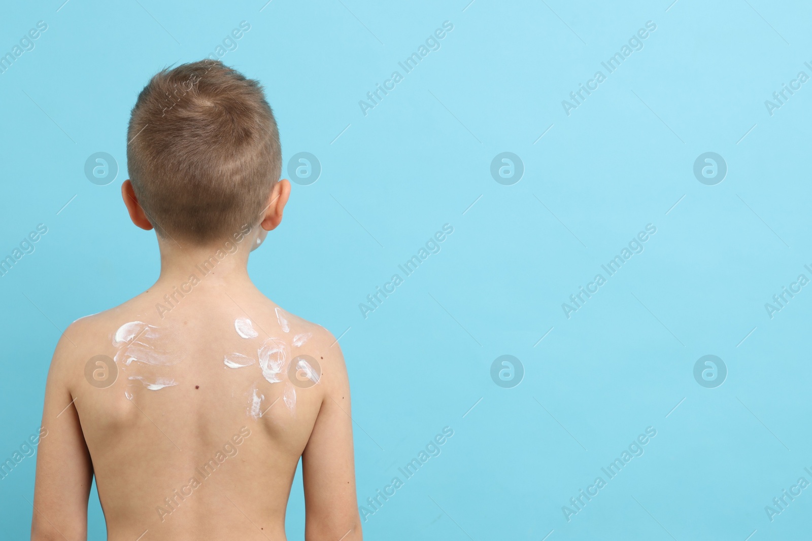 Little boy with sun protection cream on his skin against light blue background, back view. Space for text Photo of Little boy with sun protection cream on his skin against light blue background, back view. Space for text