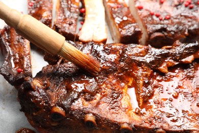 Photo of Spreading sauce with brush onto delicious spare ribs, closeup