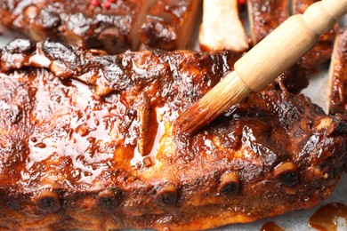 Photo of Spreading sauce with brush onto delicious spare ribs, closeup