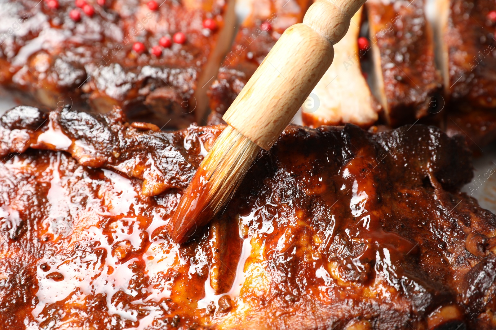 Spreading sauce with brush onto delicious spare ribs, closeup Photo of Spreading sauce with brush onto delicious spare ribs, closeup