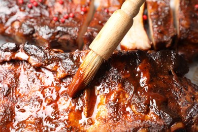 Photo of Spreading sauce with brush onto delicious spare ribs, closeup