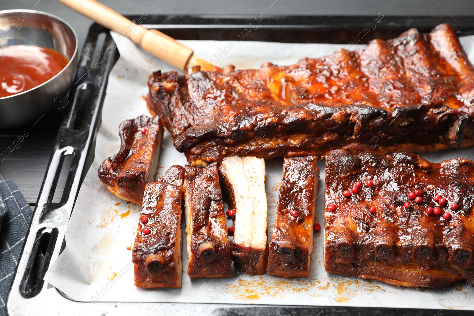 Delicious spare ribs, sauce and brush on grey table, closeup Photo of Delicious spare ribs, sauce and brush on grey table, closeup