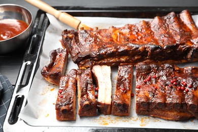 Photo of Delicious spare ribs, sauce and brush on grey table, closeup