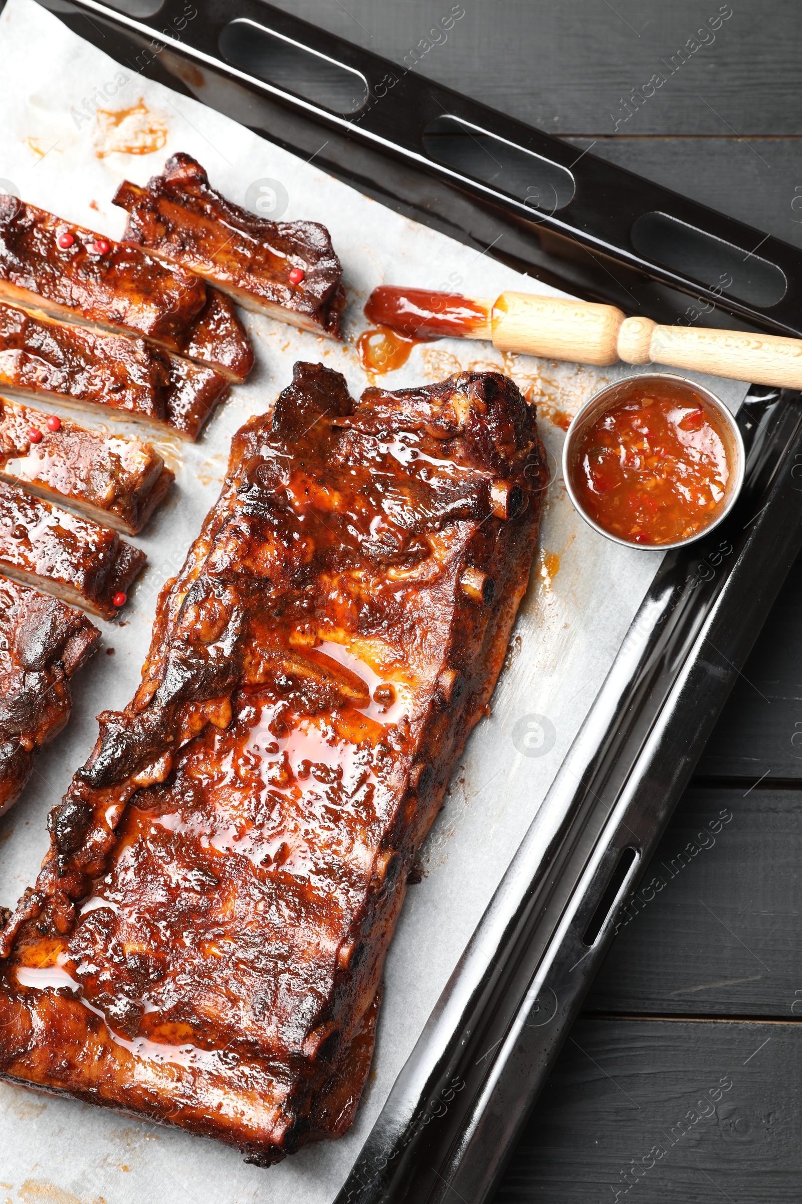 Delicious spare ribs, sauce and brush on grey wooden table, top view Photo of Delicious spare ribs, sauce and brush on grey wooden table, top view