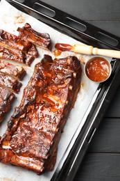 Photo of Delicious spare ribs, sauce and brush on grey wooden table, top view