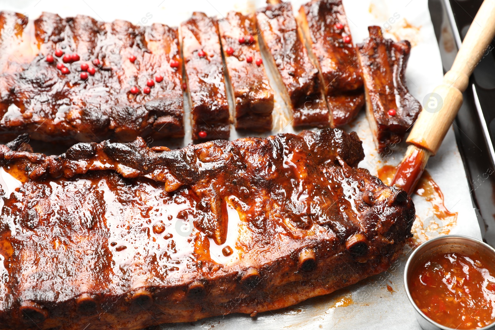 Delicious spare ribs, sauce and brush on baking tray, closeup Photo of Delicious spare ribs, sauce and brush on baking tray, closeup