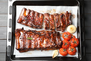 Photo of Delicious spare ribs, baked onion and sun dried tomatoes on grey wooden table, top view