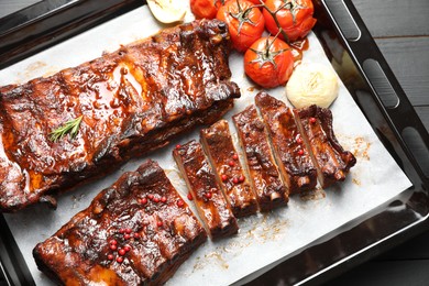 Photo of Delicious spare ribs, baked onion and sun dried tomatoes on grey wooden table, top view