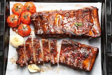 Photo of Delicious spare ribs, baked onion and sun dried tomatoes on baking tray, top view