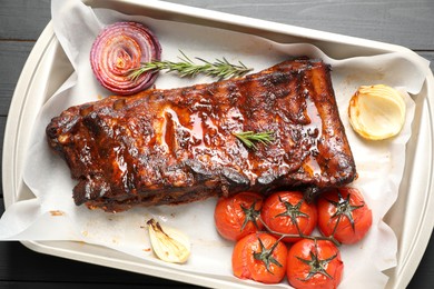 Photo of Delicious spare ribs, rosemary, baked onion and sun dried tomatoes on grey wooden table, top view