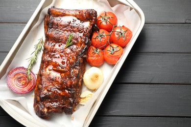 Photo of Delicious spare ribs, rosemary, baked onion and sun dried tomatoes on grey wooden table, top view. Space for text
