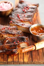 Photo of Delicious spare ribs, sauce and brush on grey table, closeup
