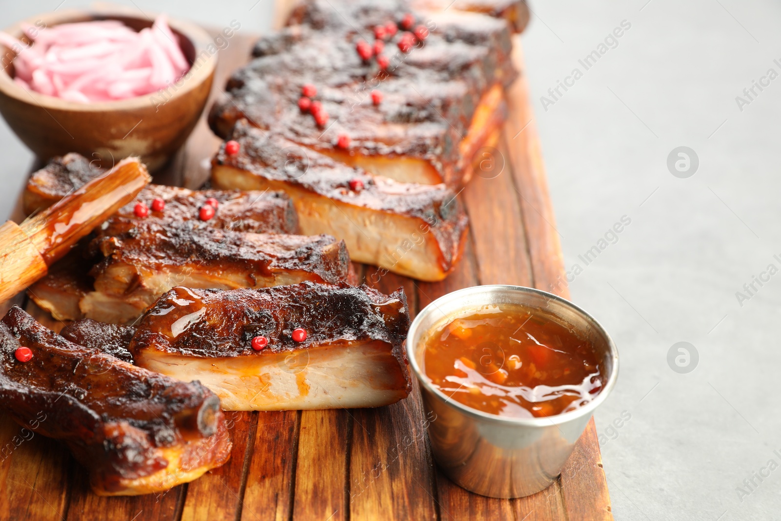 Delicious spare ribs, sauce and brush on grey table, closeup Photo of Delicious spare ribs, sauce and brush on grey table, closeup