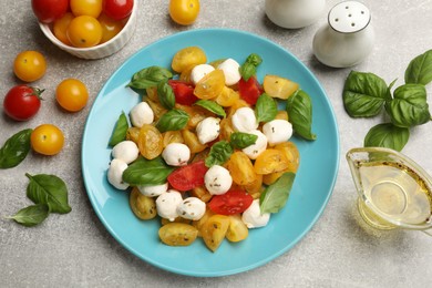 Photo of Tasty salad with yellow tomatoes, basil and mozzarella cheese on light grey table, flat lay