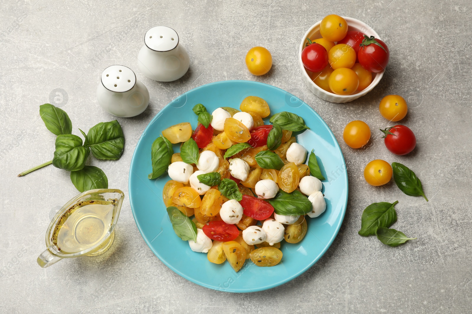 Tasty salad with yellow tomatoes, basil and mozzarella cheese on light grey table, flat lay Photo of Tasty salad with yellow tomatoes, basil and mozzarella cheese on light grey table, flat lay