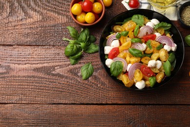 Photo of Tasty salad with yellow tomatoes, basil, onion and mozzarella cheese on wooden table, flat lay. Space for text