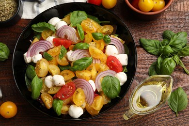 Photo of Tasty salad with yellow tomatoes, basil, onion and mozzarella cheese on wooden table, flat lay