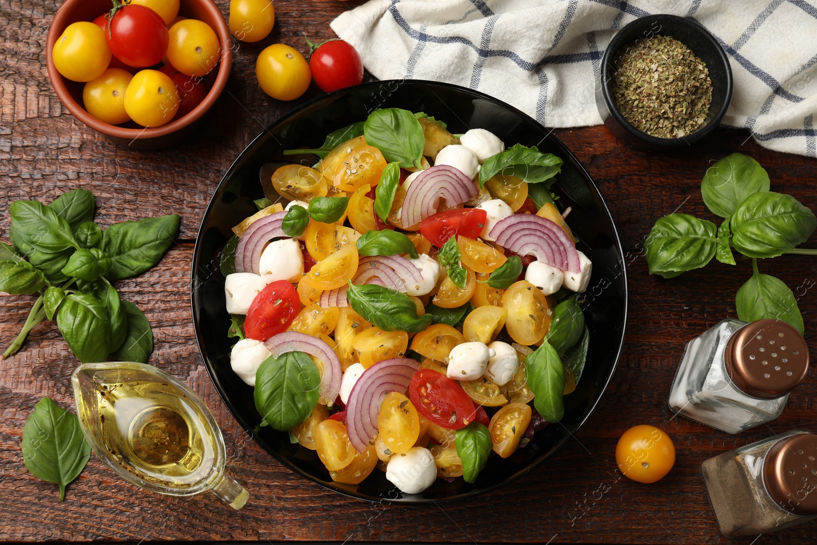 Tasty salad with yellow tomatoes, basil, onion and mozzarella cheese on wooden table, flat lay Photo of Tasty salad with yellow tomatoes, basil, onion and mozzarella cheese on wooden table, flat lay