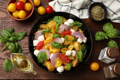 Photo of Tasty salad with yellow tomatoes, basil, onion and mozzarella cheese on wooden table, flat lay
