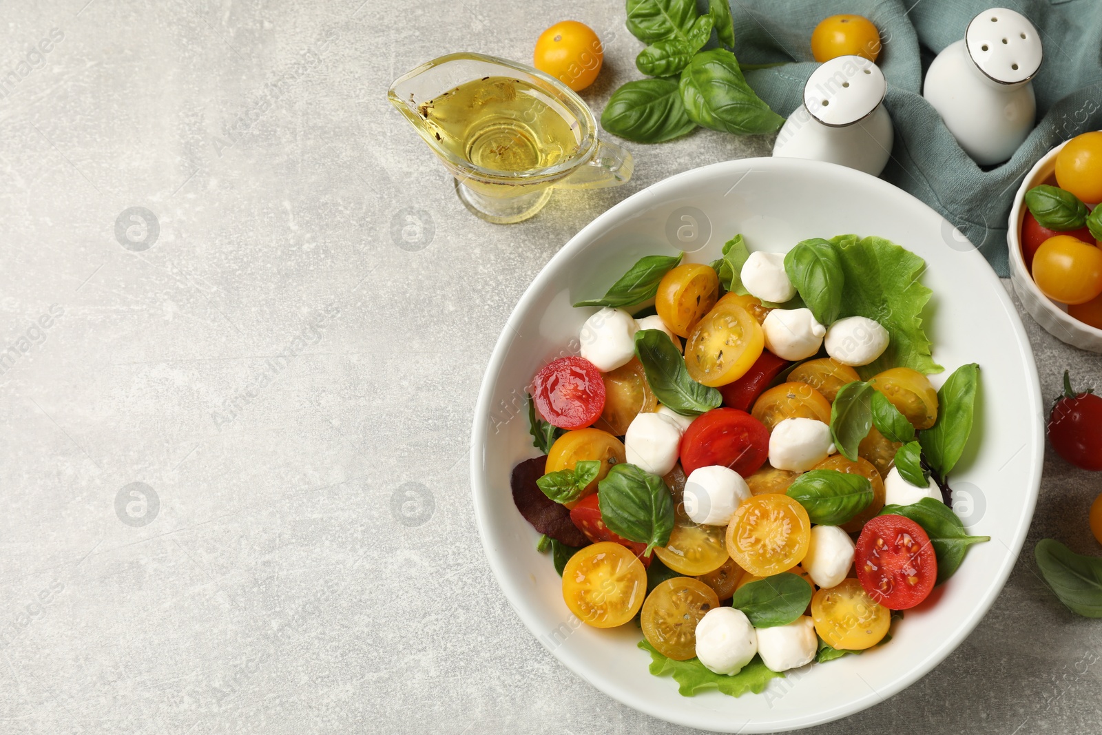 Tasty salad with yellow tomatoes, basil and mozzarella cheese on light grey table, flat lay. Space for text Photo of Tasty salad with yellow tomatoes, basil and mozzarella cheese on light grey table, flat lay. Space for text
