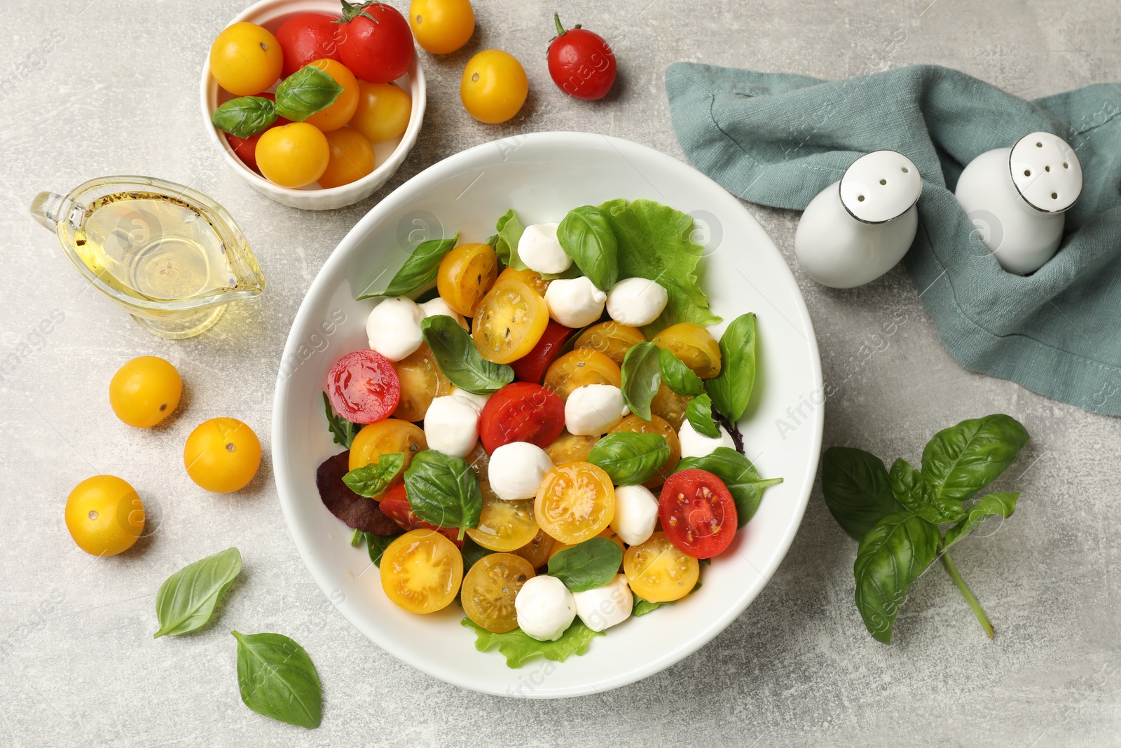 Tasty salad with yellow tomatoes, basil and mozzarella cheese on light grey table, flat lay Photo of Tasty salad with yellow tomatoes, basil and mozzarella cheese on light grey table, flat lay