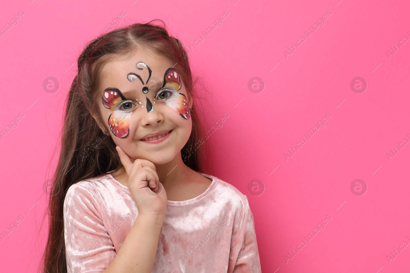 Cute girl with butterfly face painting on pink background, space for text Photo of Cute girl with butterfly face painting on pink background, space for text