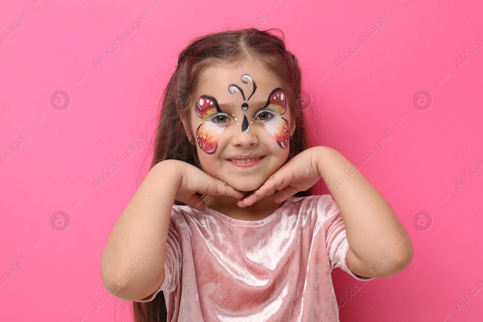 Cute girl with butterfly face painting on pink background Photo of Cute girl with butterfly face painting on pink background