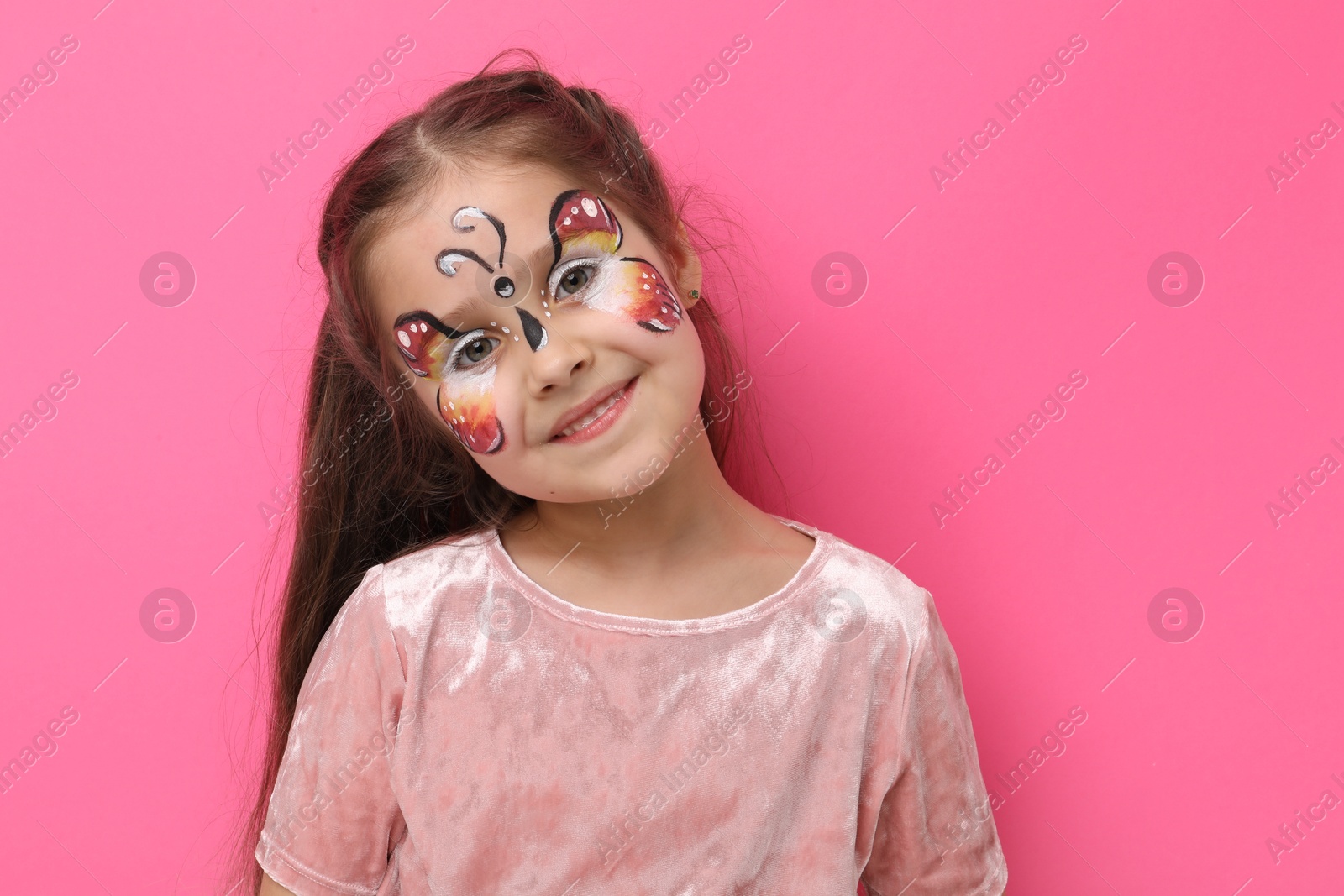 Cute girl with butterfly face painting on pink background Photo of Cute girl with butterfly face painting on pink background