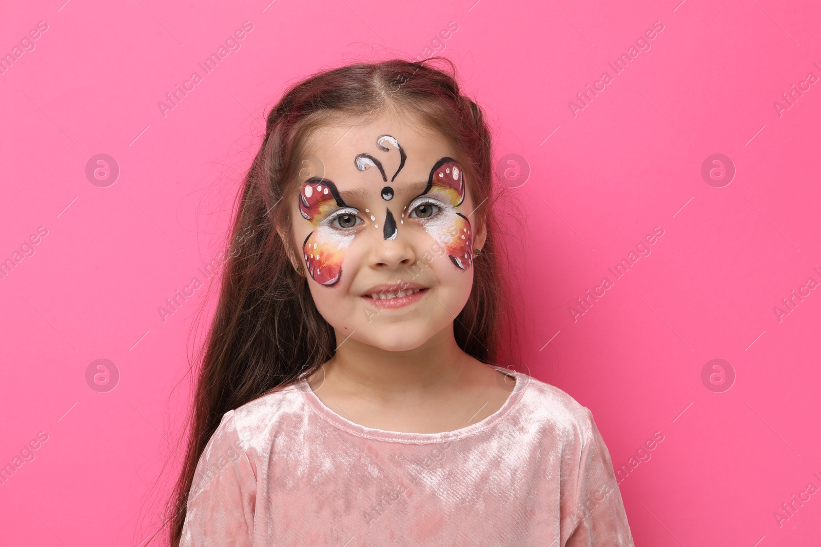 Cute girl with butterfly face painting on pink background Photo of Cute girl with butterfly face painting on pink background
