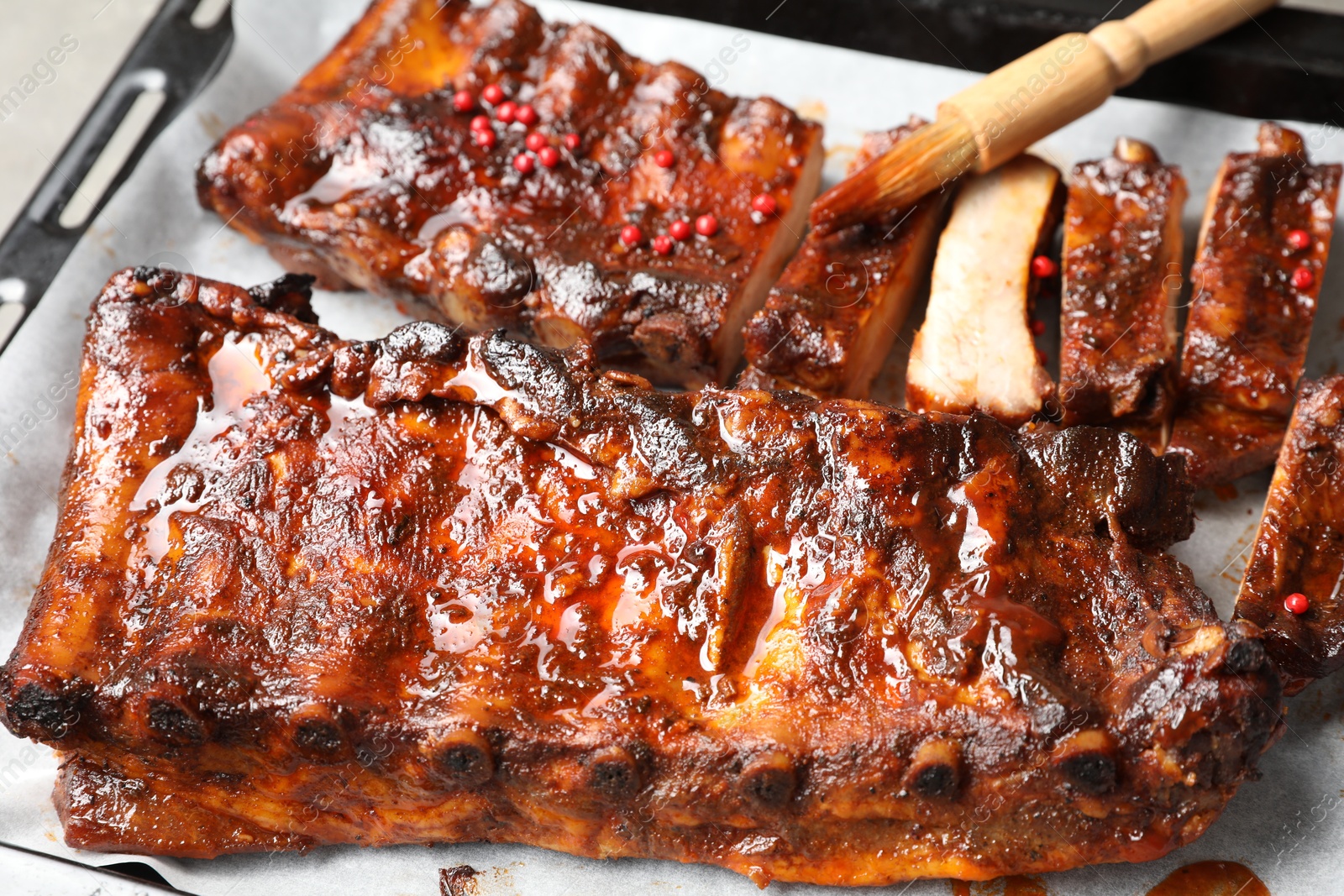Spreading sauce with brush onto delicious spare ribs at baking tray, closeup Photo of Spreading sauce with brush onto delicious spare ribs at baking tray, closeup