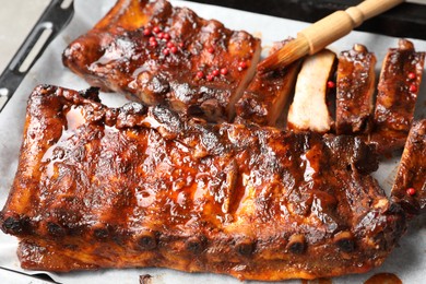 Photo of Spreading sauce with brush onto delicious spare ribs at baking tray, closeup