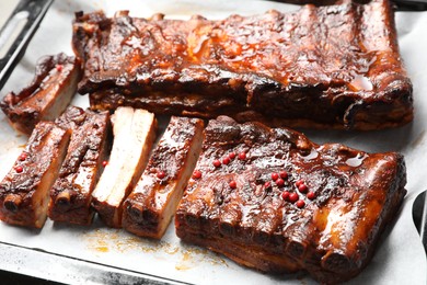 Photo of Delicious spare ribs on baking tray, closeup