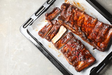 Photo of Delicious spare ribs on grey textured table, top view. Space for text