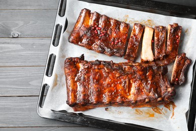 Photo of Delicious spare ribs on grey wooden table, top view