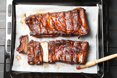Photo of Delicious spare ribs and brush on grey wooden table, top view