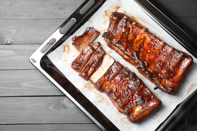 Photo of Delicious spare ribs on grey wooden table, top view