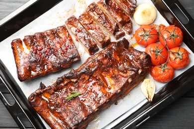 Photo of Delicious spare ribs, baked onion and sun dried tomatoes on grey wooden table, top view