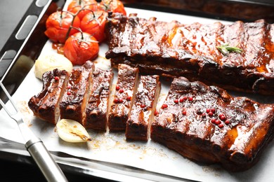Photo of Delicious spare ribs, onion and sun dried tomatoes on baking tray, closeup