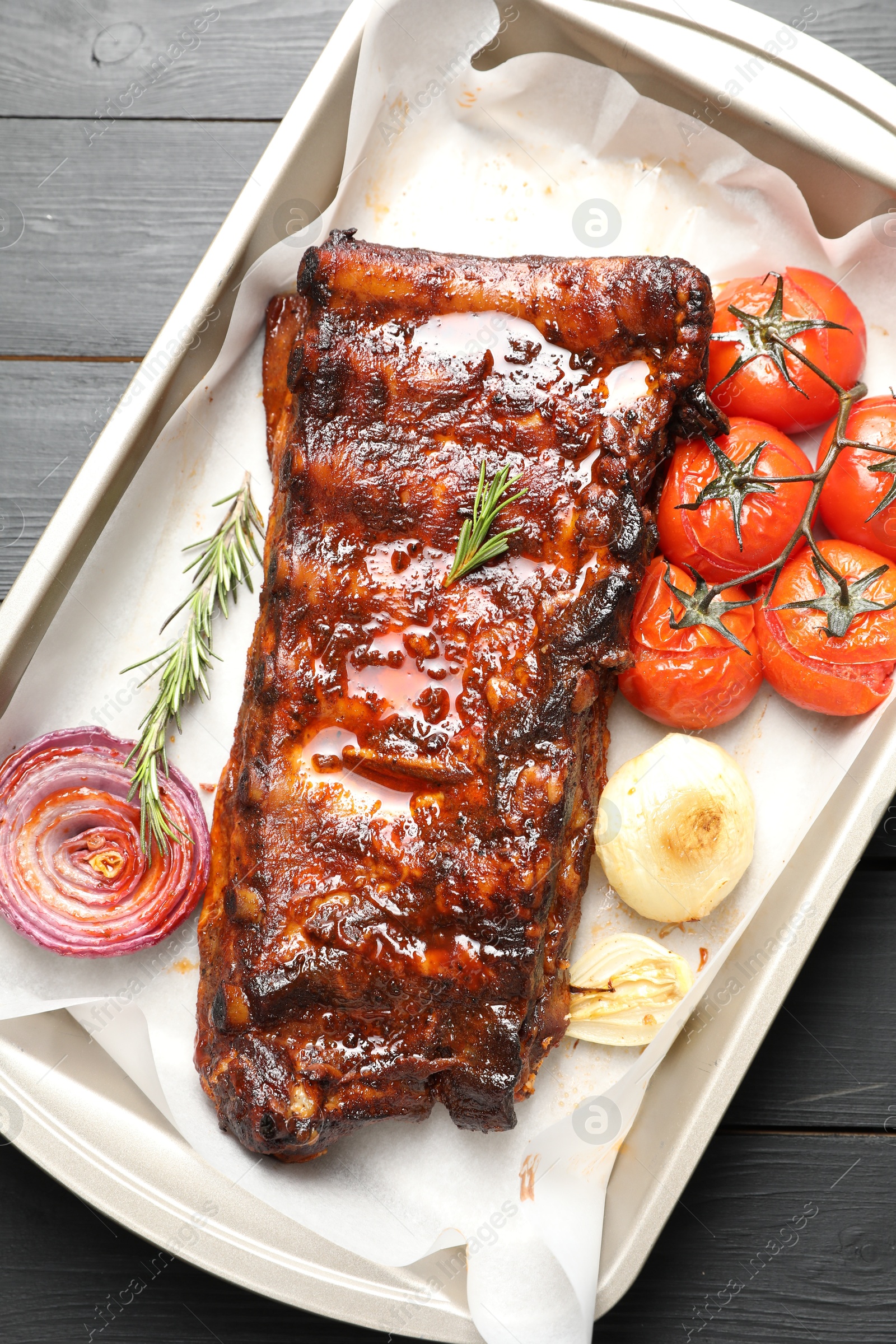 Delicious spare ribs, rosemary, baked onion and sun dried tomatoes on grey wooden table, top view Photo of Delicious spare ribs, rosemary, baked onion and sun dried tomatoes on grey wooden table, top view