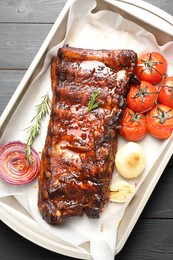 Photo of Delicious spare ribs, rosemary, baked onion and sun dried tomatoes on grey wooden table, top view
