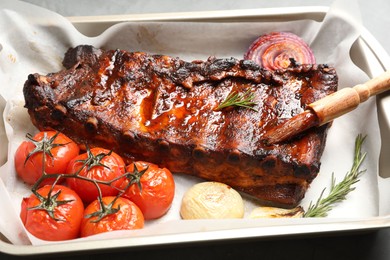 Photo of Delicious spare ribs, rosemary, baked onion and sun dried tomatoes on grey table, closeup