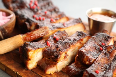 Photo of Delicious pork ribs and brush on grey table, closeup