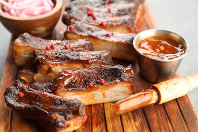 Photo of Delicious pork ribs, sauce and brush on grey table, closeup