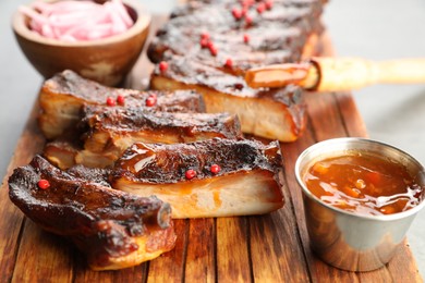 Photo of Delicious pork ribs, sauce and brush on grey table, closeup
