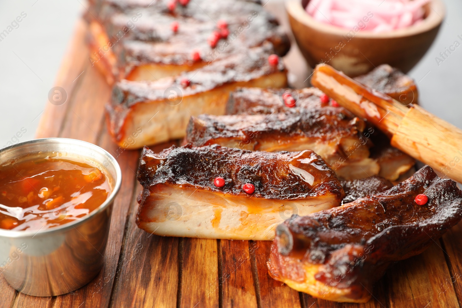 Delicious pork ribs, sauce and brush on grey table, closeup Photo of Delicious pork ribs, sauce and brush on grey table, closeup